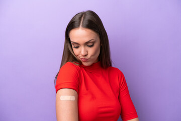 Young caucasian woman wearing band aid isolated on purple background with sad expression