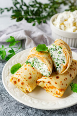 Pancakes stuffed with cottage cheese and herbs on a white plate