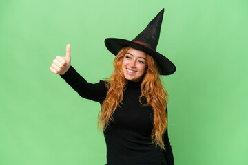 Young caucasian woman costume as witch isolated on green screen chroma key background giving a thumbs up gesture