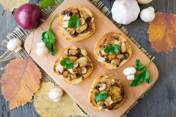 Italian bruschetta with champignons and caramelized red onions on a wooden background. Selective...