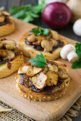 Italian bruschetta with champignons and caramelized red onions on a wooden background. Selective focus