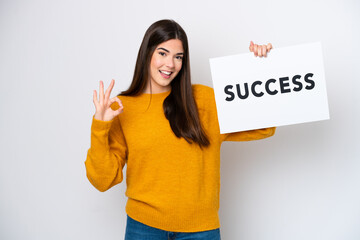 Young Brazilian woman isolated on white background holding a placard with text SUCCESS and celebrating a victory