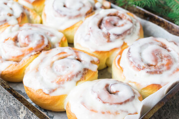 Homemade Cinnabon Buns with Cinnamon and Cream on white plate on wooden table and napkin. Wooden background. Selective focus