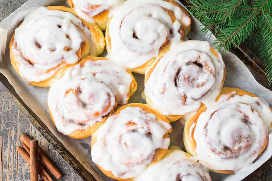 Homemade Cinnabon Buns with Cinnamon and Cream on white plate on wooden table and napkin. Wooden background. Selective focus