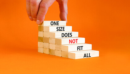 One size does not fit all symbol. Concept words One size does not fit all on wooden blocks. Businessman hand. Beautiful orange background. One size does not fit all business concept. Copy space. - obrazy, fototapety, plakaty