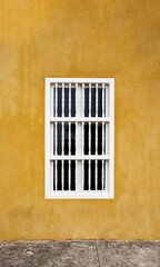 Fototapeta na wymiar Yellow colorful wall with a white window in caribbean house.