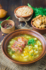 Pea soup. Traditional soup with peas, vegetables and smoked ribs served in a ceramic plate. Wooden background. Selective focus