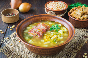 Pea soup. Traditional soup with peas, vegetables and smoked ribs served in a ceramic plate. Wooden background. Selective focus