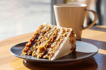 A piece of carrot cake on the table with a cup of coffee or tea close-up. Selective focus