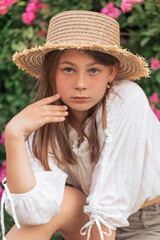 Summer stories of a little girl. White T-shirt. Straw hat. Pink roses.