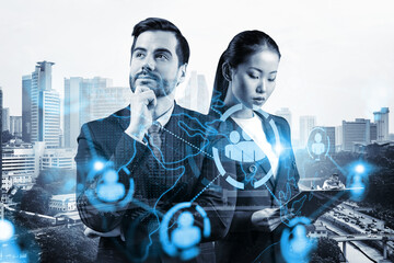 Fototapeta Businessman and businesswoman as a SMM specialists thinking about development of social media marketing strategy to achieve business goals. Hologram icons over Kuala Lumpur background. obraz