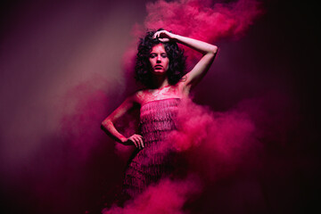 High fashion photo of a beautiful elegant young woman in flying pink dry paints. indian Holi...