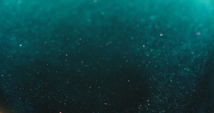 Bokeh light overlay. Blur glitter texture. Shimmering water bubbles. Defocused verdigris green blue orange color particles on dark abstract background.