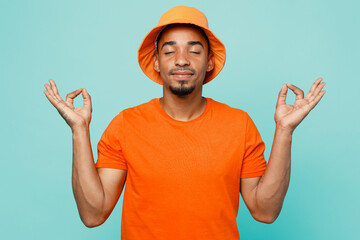 Young man of African American ethnicity in orange t-shirt hat hold spread hand in yoga om aum...