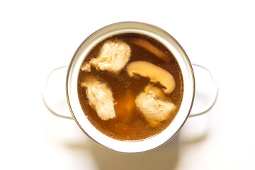 Pot of pork cartilage and shiitake mushroom soup with herbs isolated on white background.
