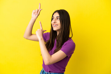 Young caucasian woman isolated on yellow background pointing with the index finger a great idea