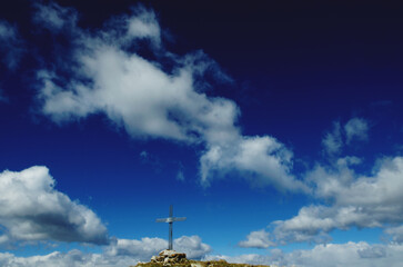 Obraz premium Cloudy sky and cross on the top of Mount Pes Masoni, Lombardy, Italy 