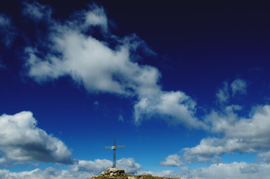 Cloudy sky and cross on the top of Mount Pes Masoni, Lombardy, Italy 