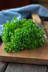 Bunch of curly parsley on cutting board with kitchen towel and knife