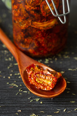 Dried tomatoes on a wooden spoon and in a glass jar. Harvest conservation