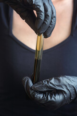 Test tube with crude oil in hands with rubber gloves