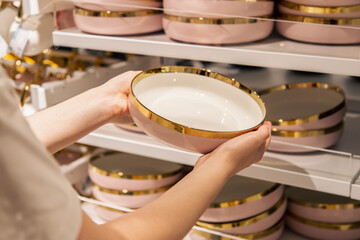 Woman holding a plate in the store, the concept of choosing dishes.