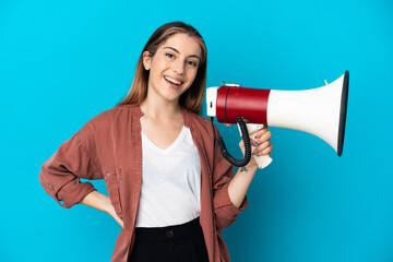 Young caucasian woman isolated on blue background holding a megaphone and smiling