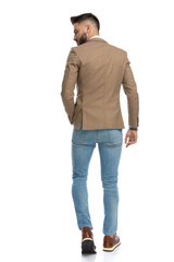 rear view of man in blue jeans looking over shoulder and walking