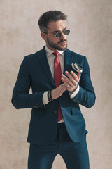 sexy bearded guy in elegant suit looking to side and rubbing palms