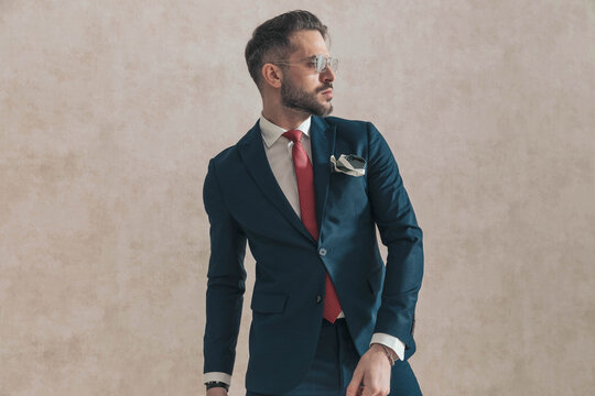 sexy bearded man wearing navy blue suit with red tie and handkerchief