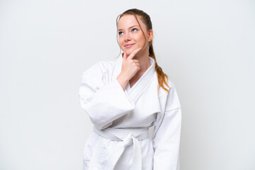 Young caucasian girl doing karate isolated on white background having doubts