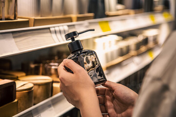 Close up, a dispenser for liquid soap in female hands in the store.