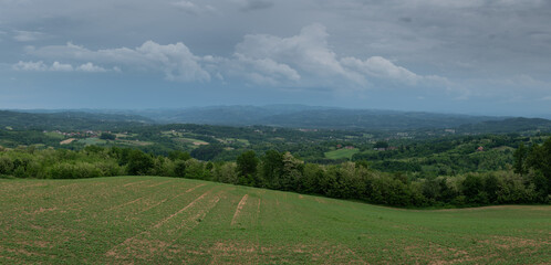 Hilly village and mountain in haze with dark cloudy sky, rural landscape