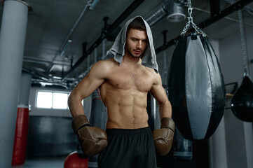Fototapeta na wymiar Tired boxer with masculine body in boxing gloves