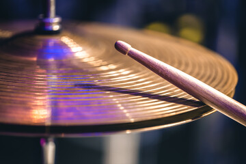 Hi-hat close-up of plates with drumsticks on a background of colored lanterns.