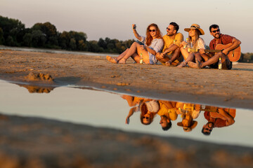 Friends taking selfie on river beach