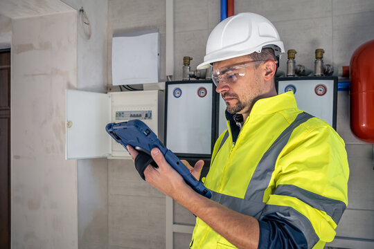 Electrical technician looking focused while working in a switchboard with fuses.