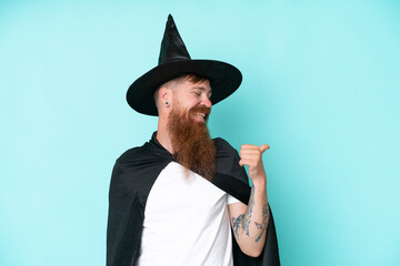 Young wizard in halloween isolated on blue background pointing to the side to present a product