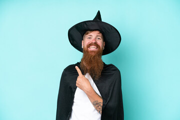 Young wizard in halloween isolated on blue background pointing to the side to present a product