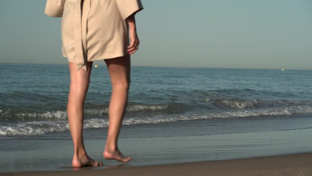 Mujer joven blanca caminando descalza en la playa en el amanecer en el mediterr&aacute;neo