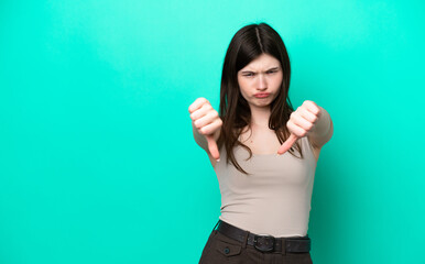 Fototapeta premium Young Russian woman isolated on green background showing thumb down with two hands