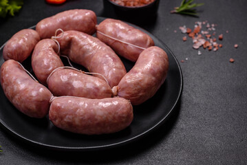 Raw barbecue sausages on a wooden cutting board with spices and herbs