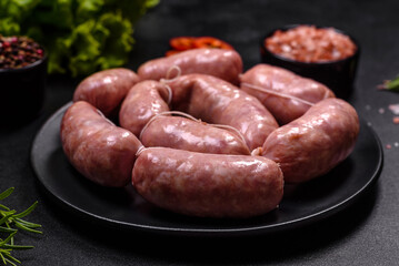 Raw barbecue sausages on a wooden cutting board with spices and herbs