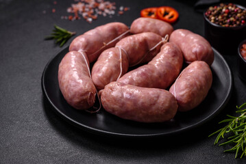 Raw barbecue sausages on a wooden cutting board with spices and herbs
