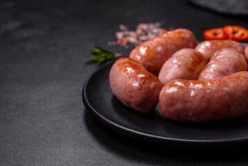 Grilled sausages with spices and herbs on a black background