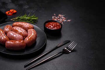Grilled sausages with spices and herbs on a black background
