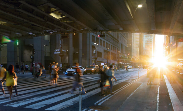 Sunlight shining on people walking across a busy street crosswalk at Grand Central Station in Manhattan New York City