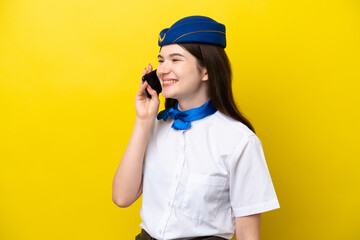 Airplane stewardess Russian woman isolated on yellow background keeping a conversation with the mobile phone