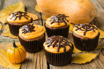Pumpkin muffins with chocolate decor and cream of cottage cheese on Halloween. Style vintage. Selective focus
