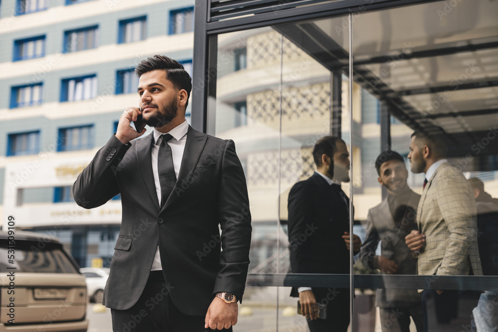 Wall mural portrait of a business man outdoors using the phone against the backdrop of a glass building downtow